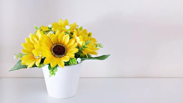 Artificial sunflowers bouquet in pot on white shelf with white background, copy space for text ,flora home decor ,home decoration ,Interior ,mother\'s day ,still life ,women\'s day festive background