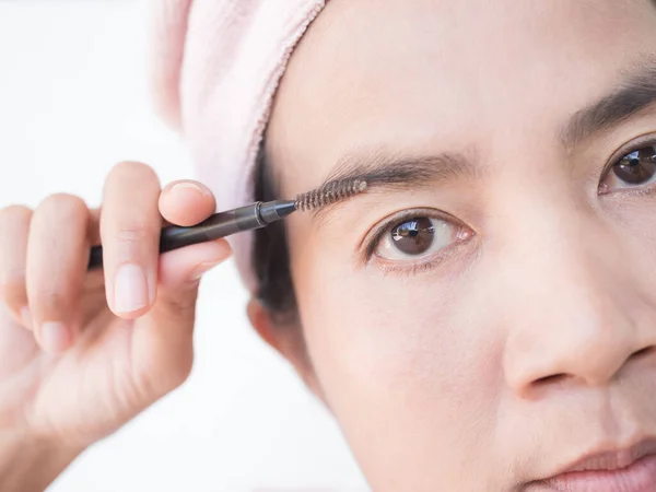 Woman Draw eyebrows Eyebrow Brush Close up,Girl Shaping brows Brushing Eyebrows,Portrait Makeup Face Beauty Cosmetic,Authentic Skin Tan and Black Eyes Asian Thailand.