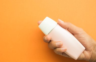 Şişe Kozmetik Model Paketi Plastik Ürün Üretim Kremi Konteynır Güzellik Yazı, Turuncu Arkaplan 'da Güneş kremi tutan kadın