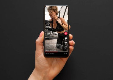 Spor salonunda çalışan bir kadının videosu sosyal medya uygulamasında cep telefonundan izleniyor.