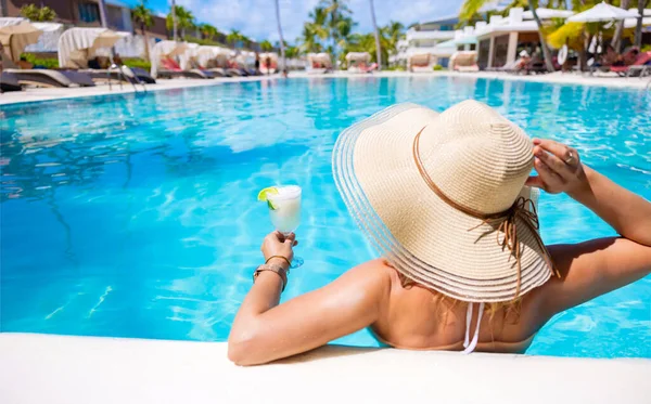休暇中にリゾートでスイミングプールでリラックスしながらカクテルのガラスを保持する女性 — ストック写真