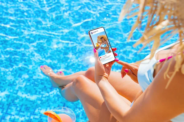 坐在游泳池边的女性在手机上使用视频分享社交媒体应用程序 — 图库照片