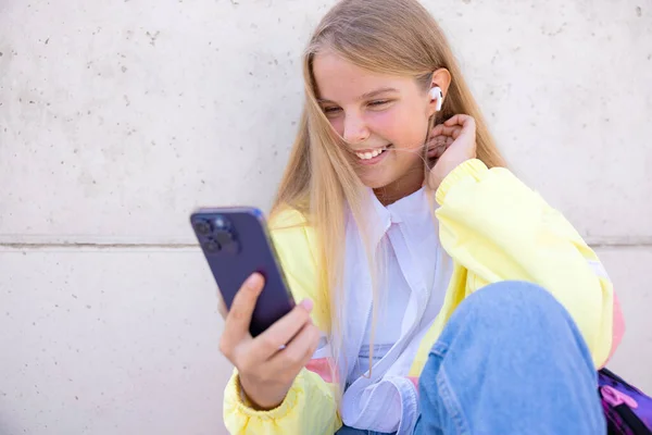 十代の女の子使用して携帯電話と音楽を聴く ストックフォト