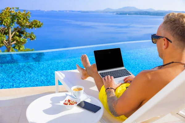 Man Werkt Laptop Computer Buiten Bij Het Zwembad Stockafbeelding