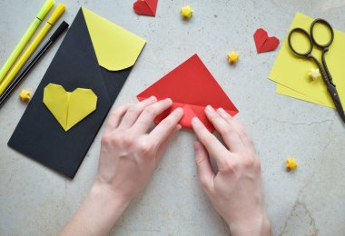 Handmade Crafting Process of a DIY Greeting Card with Origami Paper Hearts, Glue Application, Creative Stationery, Scissors, and Colorful Decorative Elements on a Light Artistic Background clipart