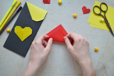 Handmade Crafting Process of a DIY Greeting Card with Origami Paper Hearts, Glue Application, Creative Stationery, Scissors, and Colorful Decorative Elements on a Light Artistic Background clipart