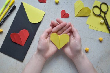 Handmade Crafting Process of a DIY Greeting Card with Origami Paper Hearts, Glue Application, Creative Stationery, Scissors, and Colorful Decorative Elements on a Light Artistic Background clipart