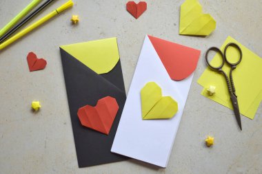 Handmade Crafting Process of a DIY Greeting Card with Origami Paper Hearts, Glue Application, Creative Stationery, Scissors, and Colorful Decorative Elements on a Light Artistic Background clipart