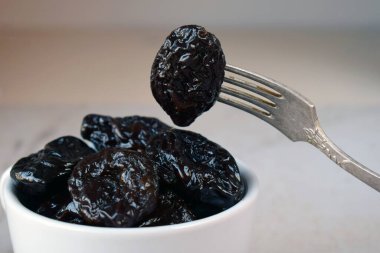 Mutfak Masasında Lezzetli Kurutulmuş Erikler Seramik Tabakta. Sağlıklı Yaşam Tarzı İçin Koyu Kırışık Meyve, Sindirimi Artırma ve Doğal Tatlılıkla Enerji