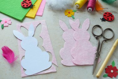 El yapımı Paskalya Tavşanı Keçeli Kalça Projesi Renkli İplikler, Makas, Kağıt Şablon ve Işık Arkaplanda Dekoratif Kalpler. Çocuklar ve Hobi Tutkuları İçin DIY Bahar Dekorasyonu Fikri