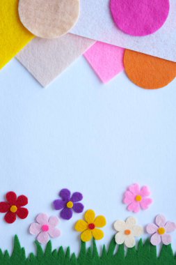 El yapımı bahar otlağı, renkli tekstil çiçekleri, DIY çiçekleri, yeşil çimenler, yumuşak yapraklar, ev dekorasyonu, yaratıcı dikiş projesi, pastel arka plan, doğadan esinlenilmiş tasarım.