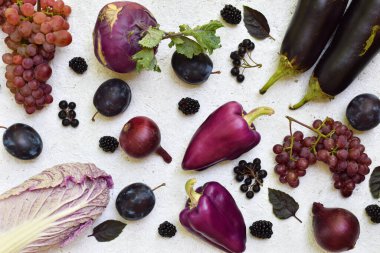 Beyaz bir zemin üzerinde mor, siyah meyve ve sebzelerin düz yatışı. Üzümler, erikler ve patlıcanlar sağlıklı gıda promosyonları için mükemmel. Vejetaryen tarifleri ve renkli mutfak tasarımları.