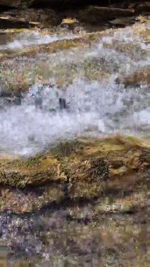 Küçük şelalenin parlak gün ışığında kayalık nehir yatağının üzerinde şelaleye yaklaşıp huzurlu bir doğa manzarası yaratması. Açık hava macera görselleri, eko yaşam tarzı temaları ve doğal kaynak korunumu için mükemmel.