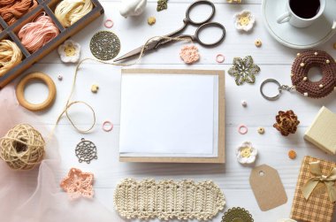 El yapımı el işi projeleri ve DIY dersleri için mükemmel beyaz ahşap bir zemin üzerine dizilmiş iplik kancaları ve makas ile yaratıcı çalışma alanının üst görünümü