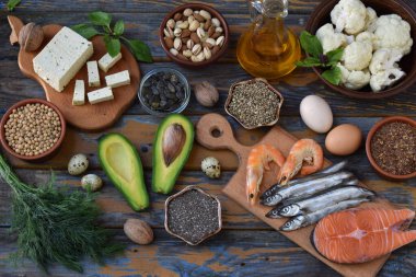 Balıklar, tohumlar, fındıklar, sebzeler, peynir, yağ ve yumurta da dahil olmak üzere kırsal ahşap yüzeyde bulunan Omega 3 zengin gıdaların çeşitliliği. Sağlık iyileştirme, beslenme desteği, beyin geliştirme, doğal organik diyet kavramı.