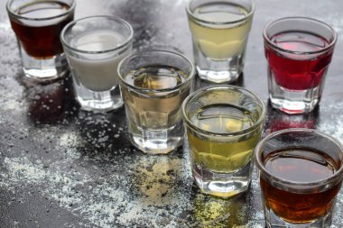 Yansıtıcı kırsal yüzeyde berrak bardaklarda çeşitli alkol çekimleri. Sosyal içki kavramı, parti kültürü, kutlama atmosferi, bar sahnesi, farklı ruhlar, ruh hali ve içecek çeşitliliği..