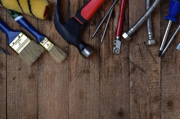 Çekiç, tornavida, ingiliz anahtarı, pense, vida ve tahta arka plandaki çiviler de dahil olmak üzere çeşitli inşaat aletlerinin üst görüntüsü. El işi kavramı, inşaat, onarım, yenileme, marangozluk, DIY