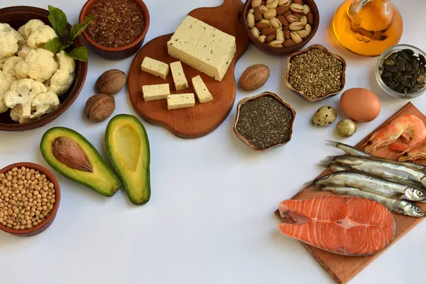 Parlak arka planda, somon, sardalya, fındık, tohum, peynir, sebze, yumurta ve yağ gibi çeşitli omega 3 içerikleri sıralanmış. Sağlıklı beslenme, dengeli beslenme, organik yaşam tarzı kavramı.