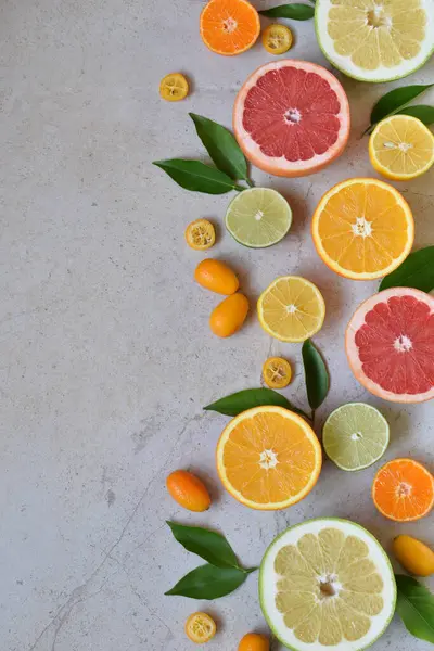 Beton yüzeye dikey olarak yerleştirilmiş portakal, greyfurt, limon, limon ve kumkat gibi dilimlenmiş narenciye meyveleri. Sağlıklı gıda kavramı, doğal vitamin kaynağı, bağışıklık desteği, detoks desteği.