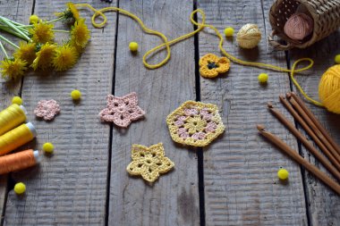 Pastel renklerde el yapımı tığ işi çiçek unsurları iplik iplikleri ve kırsal arka planda ahşap iğneler bahar sanatı düz yatakları ve sanatsal görseller için mükemmeldir.