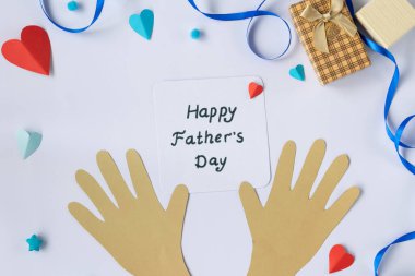 Babalar Günü için tebrik kartı kompozisyonu mavi arka planda kesme eller, mesaj ve kağıt kravat, bayram kutlamaları için düz bir üst görünüm yatıyordu