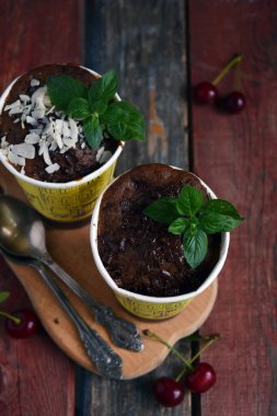 Hindistan cevizi soslu çikolatalı tatlılar ve kırsal ahşap masadaki nane yaprakları tatlı menüsü fotoğrafçılığı ve fırın promosyonları için ideal.