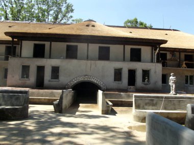 Yeni inşa edilmiş beton havuz manzarası ve yan taraftaki kemerli kapı ile inşaat halindeki ev manzarası konut arazisinin arka bahçesinde.