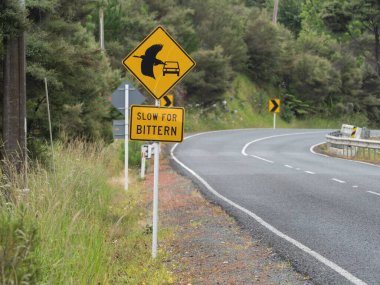 A rectangular roadside sign says 'slow for bittern'.