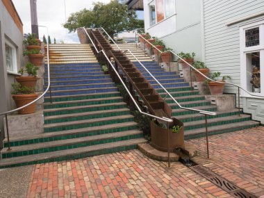 Multi coloured tiles on steps with terracotta flower pots decorate steps leading to a red tile floor area.outside Matakana Farmers Market.New Zealand
