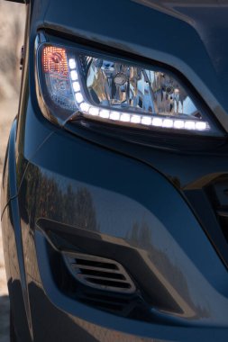 A vertical image of an RV motorhome front headlamp with LED running lights