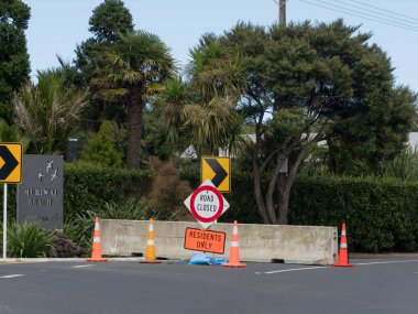 Bir yol beton levhayla kapatıldı. İşaretler 'yol kapalı' ve 'sadece sakinler girebilir' diyor. Muriwai. Yeni Zelanda. Kasırga Gabrielle 'in Sonucu.