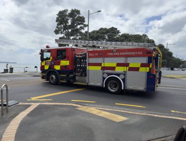 Auckland - Yeni Zelanda - 6 Şubat 2025: Yeni Zelanda 'da bir itfaiye aracı, üzerinde 111 çağrısı bulunan bir caddede seyahat ediyor. Merdiven görünür.