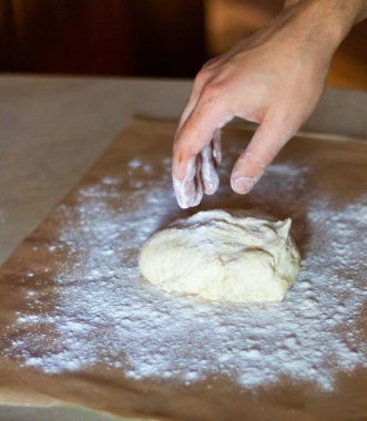 Pizza için hamur pişiriyorum. Aşçı hamuru sarar ve unu yudumlar.