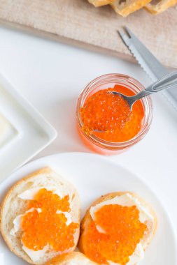 Slices of bread with red caviar on a plate, on a white background.