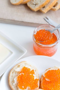 Slices of bread with red caviar on a plate, on a white background.