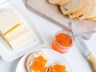 Slices of bread with red caviar on a plate, on a white background.