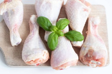 Raw chicken legs. On a white background. Salt, pepper, leaves