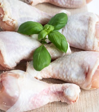 Raw chicken legs. On a white background. Salt, pepper, leaves