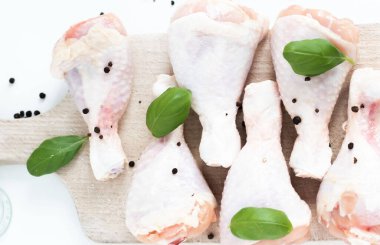 Raw chicken legs. On a white background. Salt, pepper, leaves