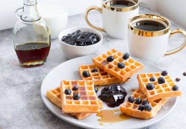 Homemade waffles with berries in a plate, on a gray background. Breakfast