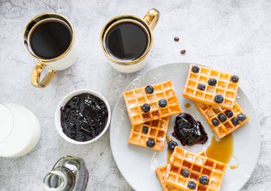 Homemade waffles with berries in a plate, on a gray background. Breakfast