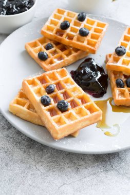 Homemade waffles with berries in a plate, on a gray background. Breakfast