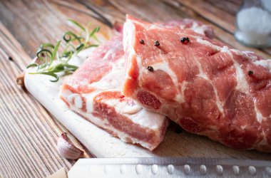 Raw pork ribs with rosemary and black pepper. on a wooden background