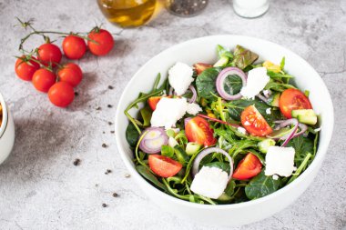 Green vegan salad from a mixture of green leaves and vegetables. On a gray background
