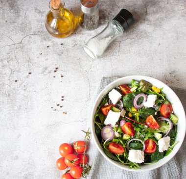 Green vegan salad from a mixture of green leaves and vegetables. On a gray background