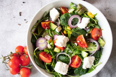 Green vegan salad from a mixture of green leaves and vegetables. On a gray background