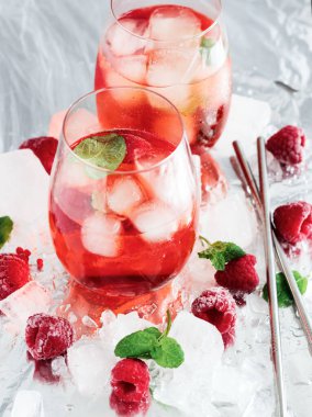 Cool cocktail with ice and mint and raspberry. On a gray background. Summer.