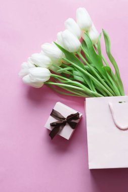 White tulips on a pink background and a gift. holiday.