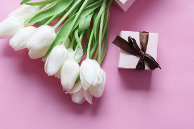 White tulips on a pink background and a gift. holiday.