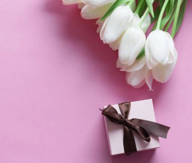 White tulips on a pink background and a gift. holiday.